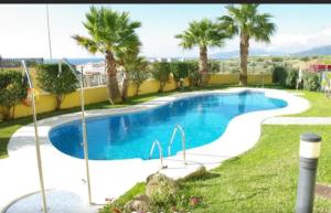 een zwembad in een tuin met palmbomen bij Coqueto estudio con acceso a piscina in Tarifa