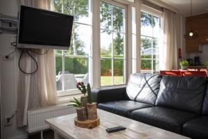 a living room with a couch and a flat screen tv at Bunckman 10 pers. bungalow in Voorthuizen +28 photos