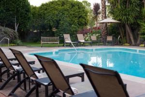 a swimming pool with chairs and a bench next to it at El Pueblo Inn in Sonoma