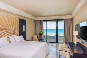 a bedroom with a bed and a desk with a view of the ocean at Iberostar Selection Kuriat Palace in Monastir