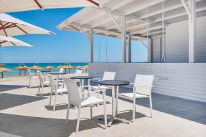 a patio with tables and white chairs and the ocean at Iberostar Selection Kuriat Palace in Monastir