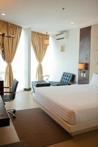 a hotel room with a large bed and two chairs at D'Hotel & Suites in Dipolog