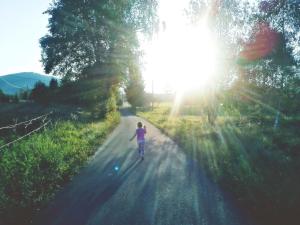 a woman walking down a road with the sun shining at Siedlisko Czarny Kot in Lądek-Zdrój