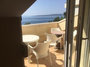 balcón con mesa, sillas y vistas al océano en Apartments Villa Astra & Pinija, en Brela