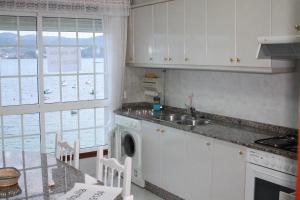 cocina con fregadero y mesa con sillas en Apartmentos Vistamar Galicia Raxó, en Raxó