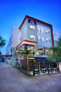 a hotel building with palm trees in front of it at Hotel Neo Candi Simpang Lima - Semarang by ASTON in Semarang