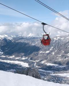 ein roter Skilift, der über einen schneebedeckten Berg fliegt in der Unterkunft Entre Giffre et Valentine in Verchaix