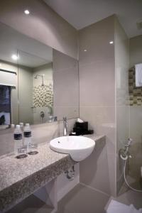 a bathroom with a white sink and a mirror at Hotel Neo Candi Simpang Lima - Semarang by ASTON in Semarang