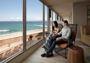 um homem e uma mulher sentados numa cadeira em frente à praia em Monterey Tides em Monterey