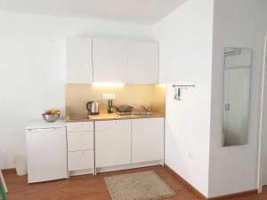 een kleine keuken met witte kasten en een spiegel bij Apartments Cvijet Mora Sreser in Sreser