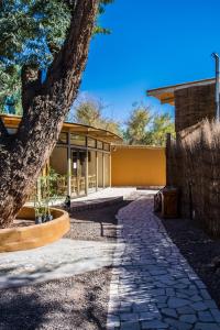 una pasarela frente a un edificio con un árbol en Hard Road Atacama, en San Pedro de Atacama