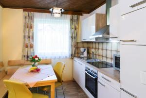 a kitchen with a wooden table and a kitchen with white cabinets at Bungalows Angelika am Klopeinersee Turnersee in Sankt Kanzian