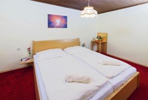 a bedroom with a large bed with white sheets at Bungalows Angelika am Klopeinersee Turnersee in Sankt Kanzian