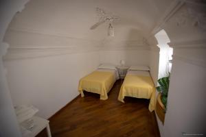 two beds in a room with white walls and wood floors at Sicily Luxury B&B in Catania