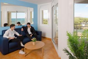 サンタ・スサナにあるApartamentos Bon Repósの三人の男がテーブルのある部屋のソファに座っている