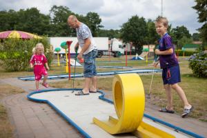 un homme plus âgé et deux enfants jouant sur un trampoline dans l'établissement HH Laambeek Mobile Home, à De Hutte