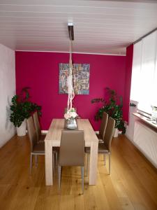 comedor con mesa de madera y paredes rosas en SC Apartment - Nürnberg Messe / Fränkisches Seenland en Schwabach