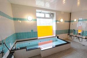 a swimming pool in a bathroom with a window at Kusatsu Kogen Youth Hostel in Kusatsu