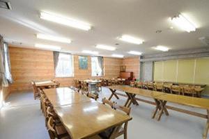 una clase con mesas y sillas en una habitación en Kusatsu Kogen Youth Hostel, en Kusatsu