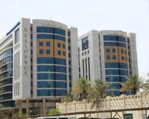 two tall buildings with palm trees in front of them at Saray Musheireb Hotel Suites and Apartment in Doha