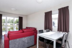 ein Wohnzimmer mit einem roten Sofa und einem Tisch in der Unterkunft MB Noordiek Chalet in Hoek