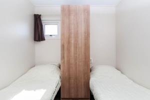 two beds in a room with a wooden partition at MB Noordiek Chalet in Hoek