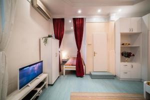 sala de estar con TV y cortinas rojas en White Pearl Apartment en Belgrado
