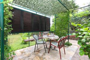 a patio with a table and chairs in a garden at Apartments Dragon in Bijela