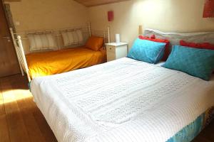 - une chambre avec un grand lit blanc et des oreillers bleus dans l'établissement Gîte des quatre chemins, à La Vineuse