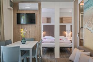 a room with a dining table and a bedroom at Mobile Homes Camping Santa Marina, Lanterna in Poreč