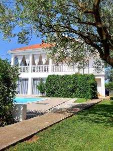 a white building with a swimming pool in front of it at Holiday Home Villa Emma in Debeljak