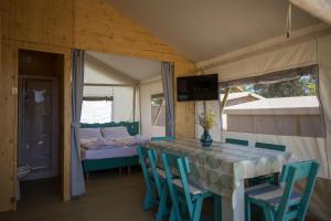 a dining room with a table and chairs and a bed at Mobile Homes Camping Santa Marina, Lanterna in Poreč