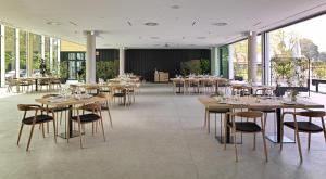 un restaurante con mesas y sillas de madera y ventanas en Noa Boutique Hotel, en Santa Cruz de Oleiros