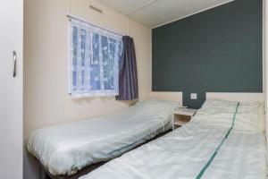 Dos camas en una habitación pequeña con ventana. en RA Reeënveld Mobile home, en Arnhem 7 fotos más