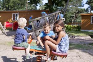 dos niños sentados en un equipo de juegos en un parque infantil en RA Reeënveld Mobile home, en Arnhem