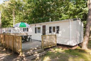 a white trailer with a deck and a table at RA Veluwe Mobile home in Arnhem
