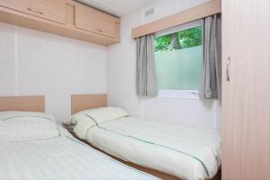two beds in a small room with a window at RA Veluwe Mobile home in Arnhem +7 photos