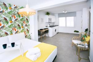 Una habitación con una cama blanca y una cocina. en MONKÓ - LEMON & TROPYCAL APARTMENT o, en Torremolinos