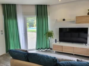 sala de estar con TV y cortinas verdes en PÉROLA D'ÓBIDOS t1 en Óbidos