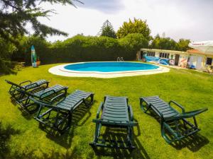 a group of lawn chairs and a swimming pool at Carcavelos Surf Hostel & Surf Camp in Carcavelos
