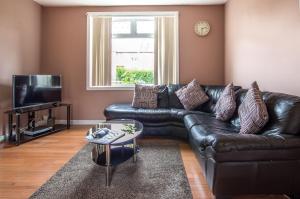 a black leather couch in a living room with a window at Montgomery Apartments - Stevensons in Edinburgh