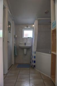 a bathroom with a tub and a sink and a bath tubermottermott at Huisje Linquenda in Moddergat