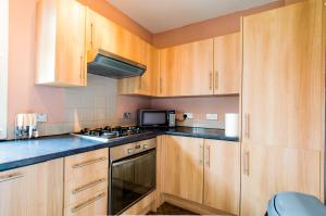 uma cozinha com armários de madeira e um forno com placa de fogão em Montgomery Apartments - Stevensons em Edimburgo