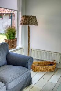 a living room with a couch and a lamp at Huisje Linquenda in Moddergat