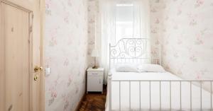 a bedroom with a white bed with pink floral wallpaper at Roosi Apartment in Pärnu