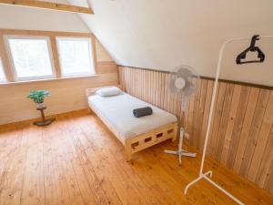 Nature Guest House في فوسو: غرفة بها سرير ومروحة أرضية