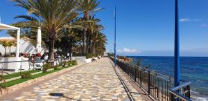 a walkway next to the ocean with palm trees at Punta Prima Pleamar in Orihuela Costa
