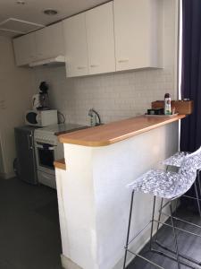 una cocina con armarios blancos, una barra y dos taburetes en Appartement Bayeux F3, en Bayeux