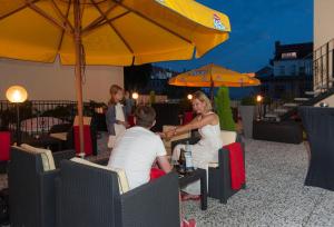 um grupo de pessoas sentadas numa mesa sob um guarda-chuva em Hotel Europa em Görlitz