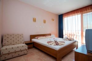 a bedroom with a bed and a chair and a window at Хотел Лагуна in Chernomorets +21 photos